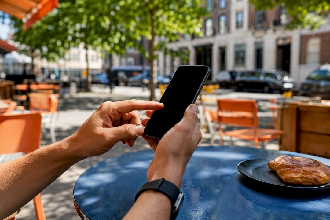 Hands holding smartphone with dark screen